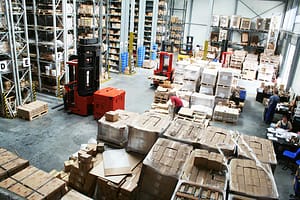 Warehouse workers in an industrial environment surrounded by pallets, racking and forklift trucks
